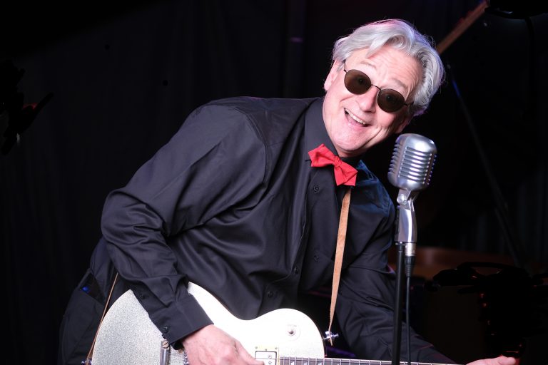 Der Musiker Jochen Hillesheim singend am Mikrofon und am Gitarre spielen