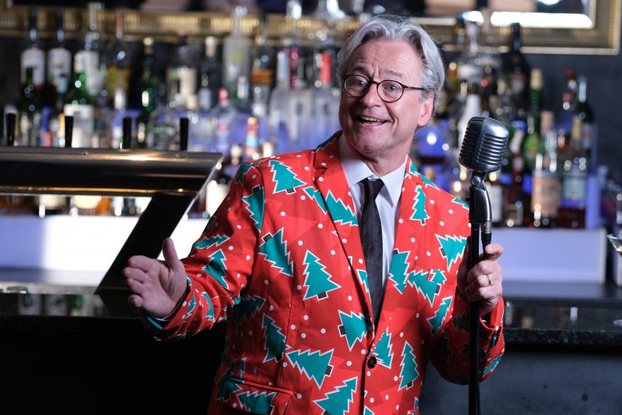 Der Musiker Jochen Hillesheim in einer Bar am Mikrofon am Singen in einem Weihnatslichem Jacket.